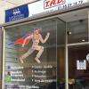 Vitrine de l'agence de déménagement au logo des Gentlemen du Déménagement, un superman en carton à la cape bleue et rouge.