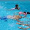 une Sirène professionnelle nage en piscine avec des enfants par la main