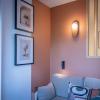 Décoration d'un coin salon aux tonalités terracotta, avec éclairage mural et claustra en bois pour structurer l'espace, un design de Laurence ARNAUD